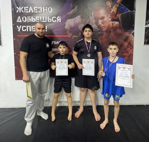 Тренер и трое ребят с медалями и грамотами